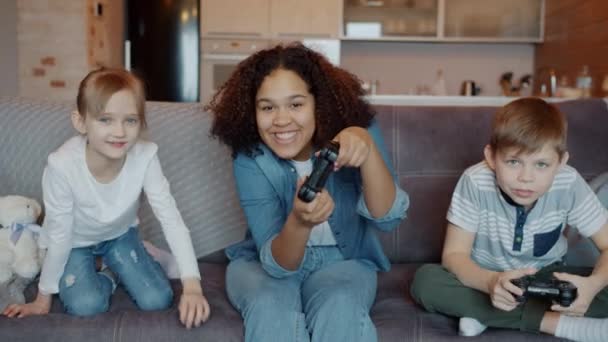 Movimento rápido de pessoas felizes babá e crianças jogando videogame e rindo se divertindo em casa — Vídeo de Stock