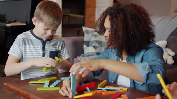 Menina afro-americana babá falando com crianças e brincando com blocos de construção no apartamento — Vídeo de Stock