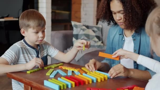 Babysitter peduli Afro-Amerika wanita bermain mainan dengan anak-anak yang patuh — Stok Video