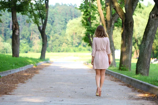 背面図 完全な成長 夏の公園でウォーキング ピンクのドレスで魅力的な若いブロンドの女性の肖像画 — ストック写真