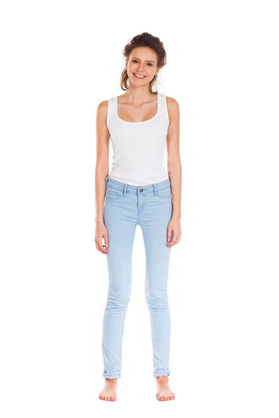 Ung kvinna i blå jeans står isolerade på en vit bak — Stockfoto