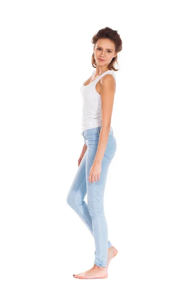 Mladá žena v modrých džínách stojící izolovaných na bílém poza — Stock fotografie