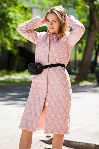 ばねの通りのピンクのコートで若い美しいブルネットの女性の肖像画 — ストック写真