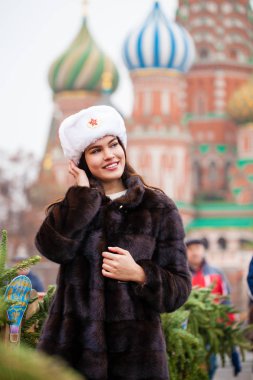 Rus güzellik. Bir kürk şapka kırmızı bir kare Moskova'da karşı beyaz şapkalı güzel bir genç kız portresi