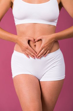 Fitness vücut parçası. Genç kadın beyaz arka plan üzerinde izole kalp işareti eller, gösterilen