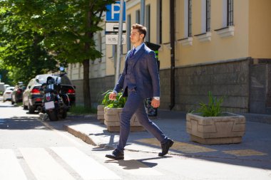 Tam büyüme iş takım elbiseli Genç bir adam portresi yolun bir yaya geçidi üzerinde haçlar.