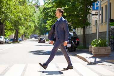 Tam büyüme iş takım elbiseli Genç bir adam portresi yolun bir yaya geçidi üzerinde haçlar.