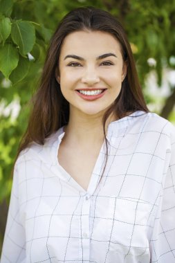 Taze ve temiz tenli, güzel, genç, mutlu esmer bir kadının açık hava yaz portresi.