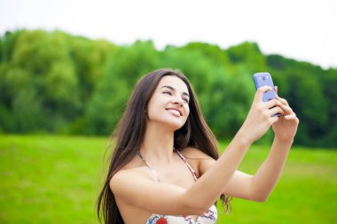 bir yaz parkta bir cep telefonuyla fotoğrafını genç güzel kız