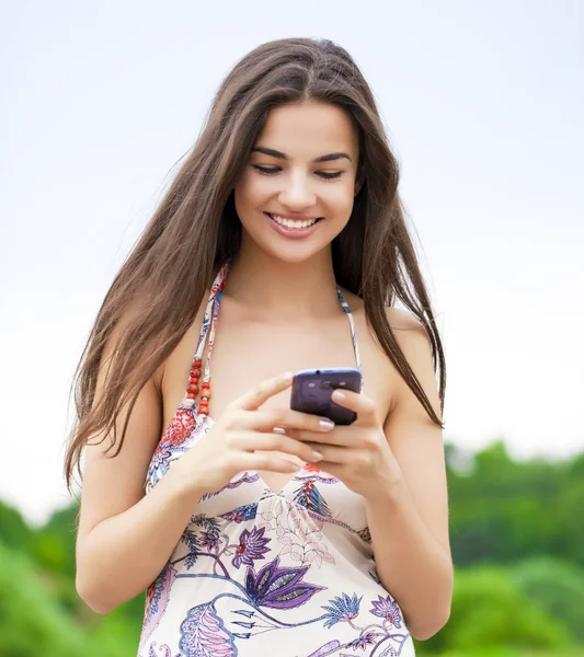 若い女性の夏の公園で電話でメッセージを読む — ストック写真