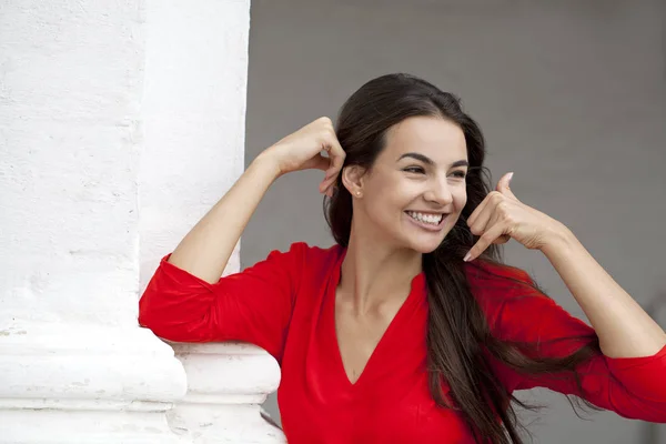 美しい女性が私をかけるジェスチャー 白い壁の背景に赤いドレスで幸せな女の子 — ストック写真