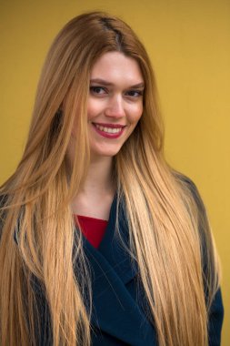 Mavi paltolu genç güzel kadın, mutlu sarışın model sarı duvara portresi