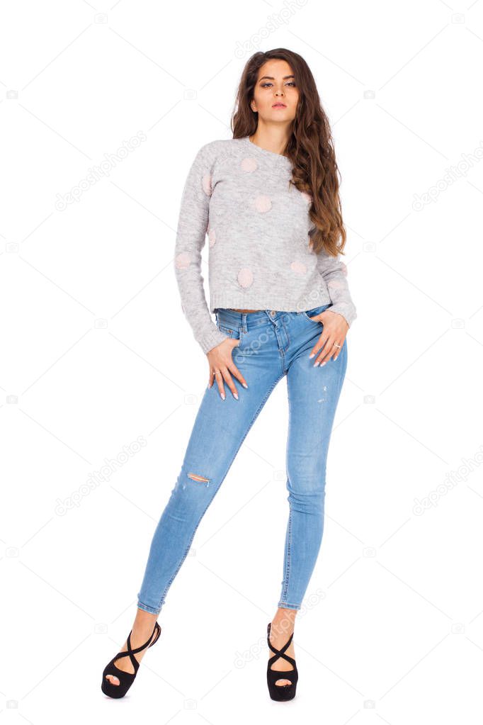 Sexy Brunette woman in blue jeans and gray sweater, isolated on white background