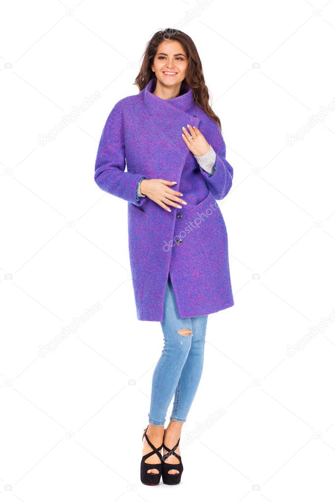 Portrait in full growth of a beautiful young woman in purple autumn coat and blue jeans, isolated on white background