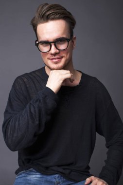 Karanlık bir arka plan üzerinde büyük gözlüklü genç bir adam portresi stüdyo