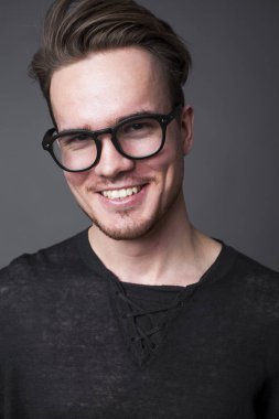 Karanlık bir arka plan üzerinde büyük gözlüklü genç bir adam portresi stüdyo