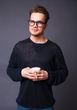 Karanlık bir arka plan üzerinde büyük gözlüklü genç bir adam portresi stüdyo