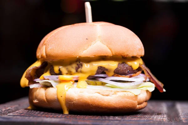 Burger with melted cheese for football fans. Big cheeseburger with melted cheese