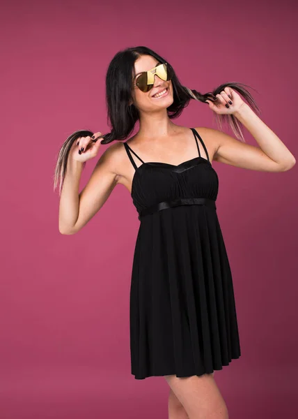 Счастливая Юная Брюнетка Черном Платье Солнечных Очках Красном Изолированном Фоне — стоковое фото