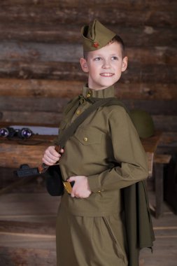 Rus çocuk bir sığınağın çubuklarından arka plan üzerinde bir dürbün ile eski Sovyet askeri üniforması giyen