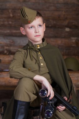 Rus çocuk bir sığınağın çubuklarından arka plan üzerinde bir dürbün ile eski Sovyet askeri üniforması giyen