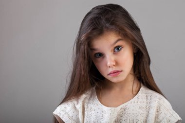Gri arka planda izole edilmiş çekici esmer küçük bir kızın portresi.