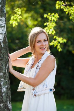 Açık havada gülümseyen güzel bir genç kadının portresi. Sarı saçlı güzel.