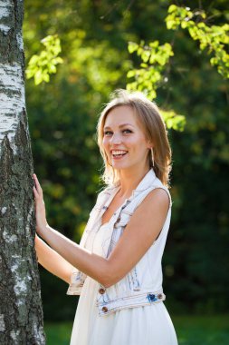 Açık havada gülümseyen güzel bir genç kadının portresi. Sarı saçlı güzel.