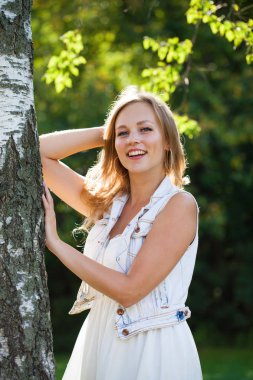 Açık havada gülümseyen güzel bir genç kadının portresi. Sarı saçlı güzel.