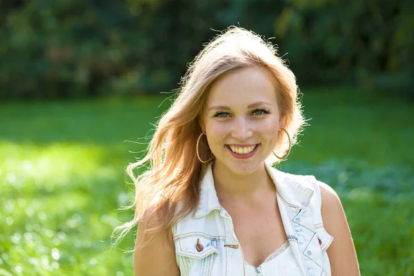 Açık havada gülümseyen güzel bir genç kadının portresi. Sarı saçlı güzel.