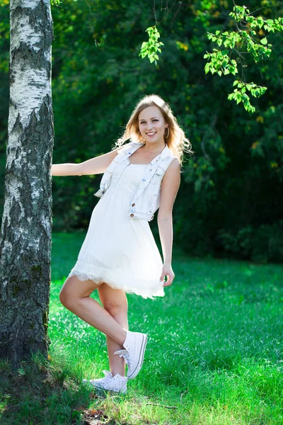夏の緑豊かな公園の背景のドレス夏白で若い美しいブロンドの女性 — ストック写真