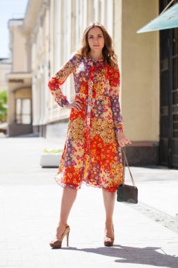 Portre tam uzunlukta içinde kırmızı çiçekler, yaz sokak açık havada Genç güzel esmer kadın