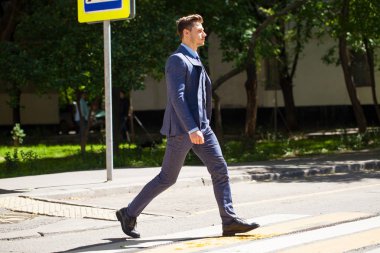 Tam büyüme iş takım elbiseli Genç bir adam portresi yolun bir yaya geçidi üzerinde haçlar.