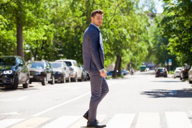 Tam büyüme iş takım elbiseli Genç bir adam portresi yolun bir yaya geçidi üzerinde haçlar.