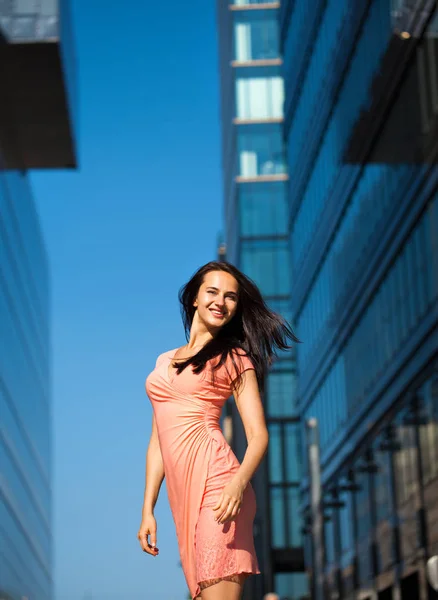 ビジネスビル街に対して セクシーなピンクのドレスで美しい若いブルネットの女性 — ストック写真