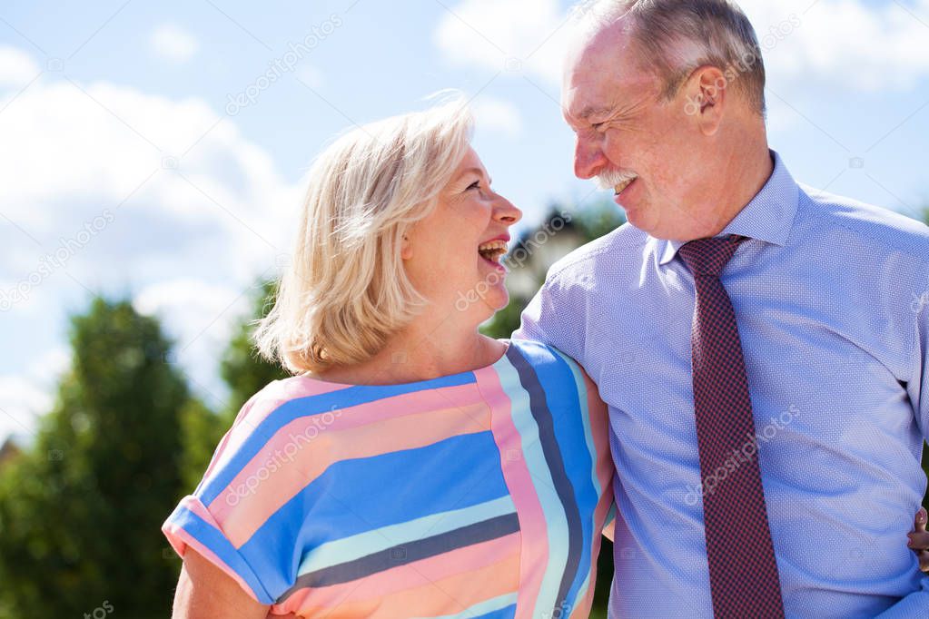 Happy senior couple walking in summer in park