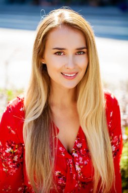 Kapalı kapılar ardında duran, kırmızı seksi elbiseli sarışın genç bir kadının portresi.