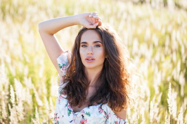 Portre yakın çekim beyaz elbiseli Genç güzel esmer kadının günbatımında alana poz