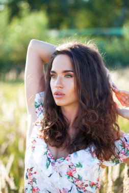 Portre yakın çekim beyaz elbiseli Genç güzel esmer kadının günbatımında alana poz