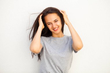 Gri tişörtlü mutlu esmer kadın, beyaz duvar arkasında izole edilmiş.