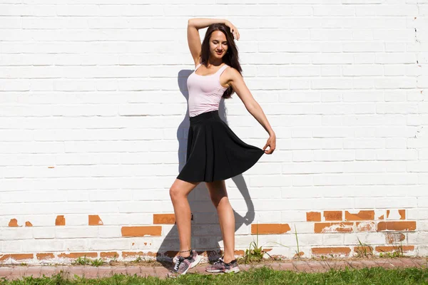 完全なボディの女性 れんが造りの白い壁に 黒のスカートで幸せな美しい若いブルネット モデル — ストック写真