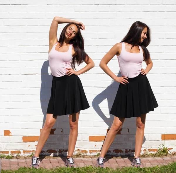 Full body women. Happy Beautiful young brunette model in black skirt, against white brick wall