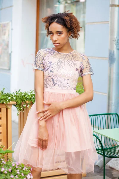 Portrait of an African model woman in pink dress, summer street outdoor