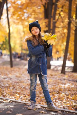 Gençler moda. Sonbahar park arka planda kot ceketli genç esmer kız portresi