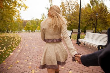 Takip et beni. Güzel genç sarışın ve kimliği belirlenemeyen adamın elini tutarak ve onunla güneşli sonbahar park yürüyüş