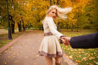 Takip et beni. Güzel genç sarışın ve kimliği belirlenemeyen adamın elini tutarak ve onunla güneşli sonbahar park yürüyüş