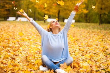 Sonbahar parkında kot pantolonlu genç sarışın kadın.