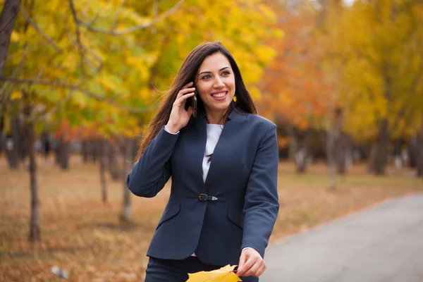 女性は電話で呼び出します 秋の公園で歩く青いスーツの幸せ成功アラブ女性実業家 — ストック写真