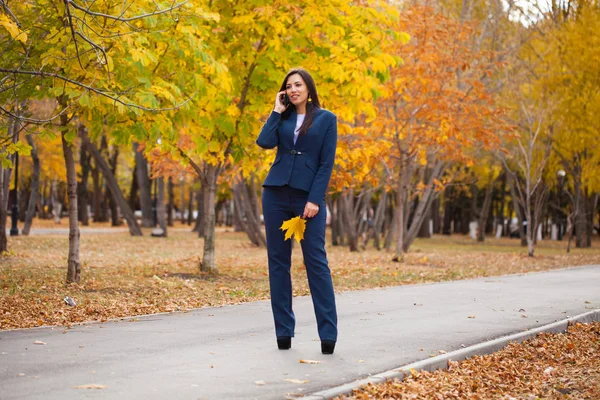 打电话的女人 愉快成功的阿拉伯女实业家在蓝色西装散步在秋季公园 — 图库照片