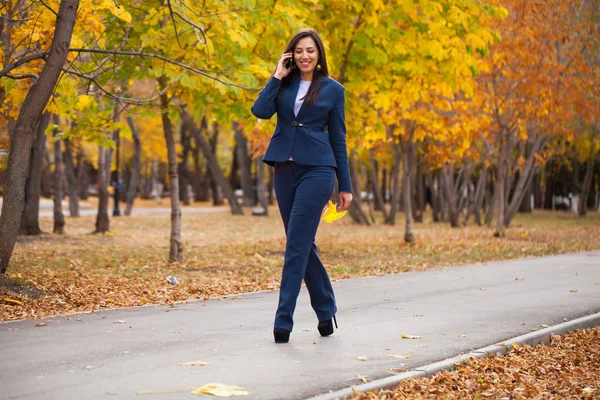 打电话的女人 愉快成功的阿拉伯女实业家在蓝色西装散步在秋季公园 — 图库照片